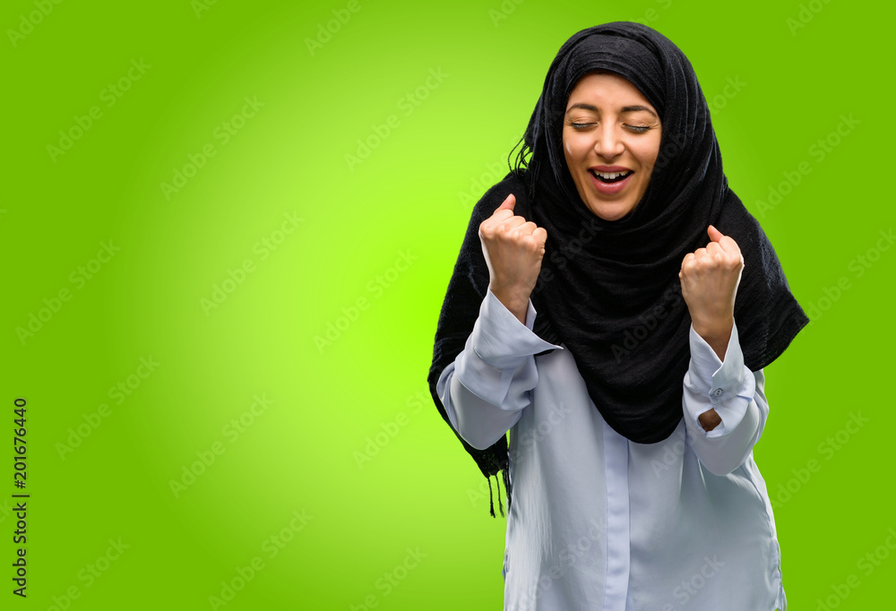 Young arab woman wearing hijab happy and excited celebrating victory expressing big success, power, energy and positive emotions. Celebrates new job joyful Young arab woman wearing hijab happy and excited celebrating victory expressing big success, power, energy and positive emotions. Celebrates new job joyful