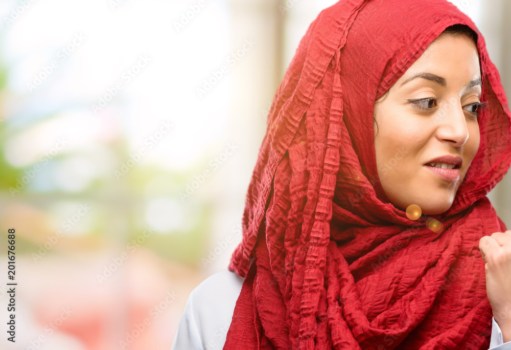 Young arab woman wearing hijab pointing away side with his finger Young arab woman wearing hijab pointing away side with his finger