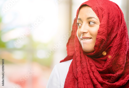 Young arab woman wearing hijab confident and happy with a big natural smile looking side