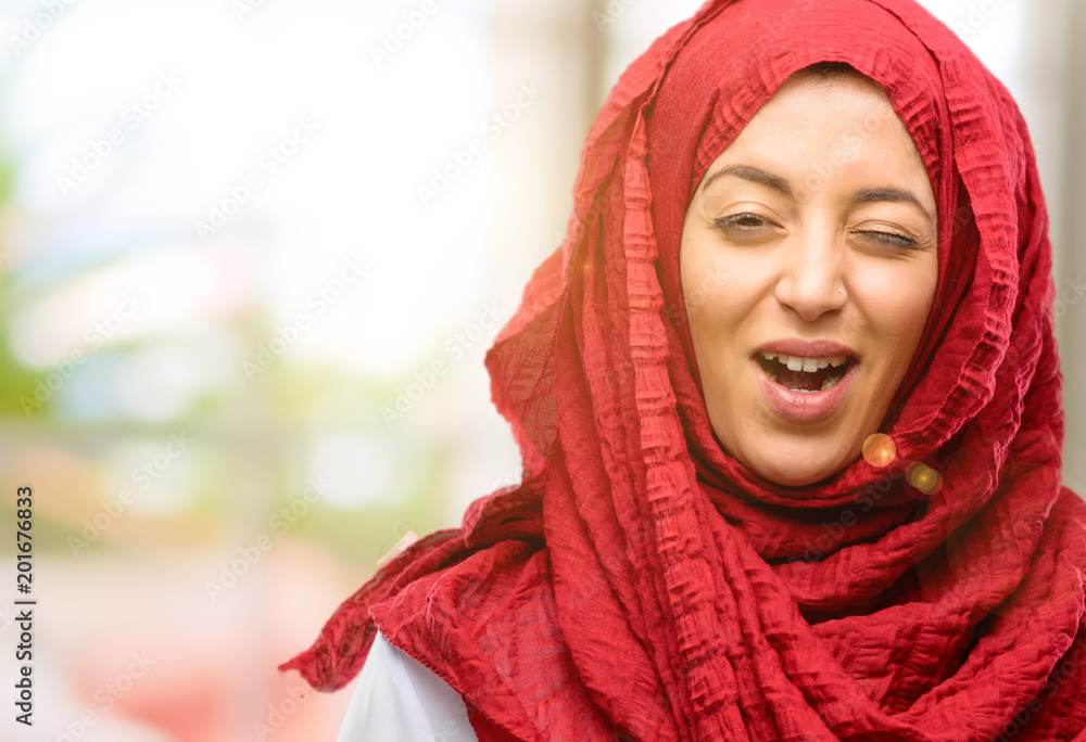 Young arab woman wearing hijab blinking eyes with happy gesture Young arab woman wearing hijab blinking eyes with happy gesture