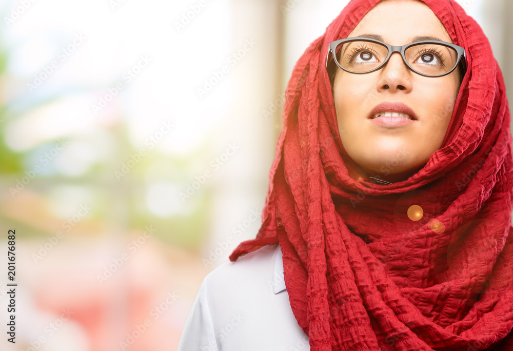 Young arab woman wearing hijab confident and happy with a big natural smile laughing looking up Young arab woman wearing hijab confident and happy with a big natural smile laughing looking up