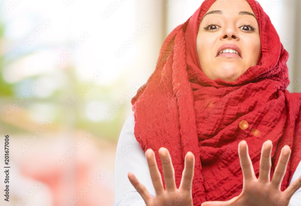 Young arab woman wearing hijab disgusted and angry, keeping hands in stop gesture, as a defense, shouting Young arab woman wearing hijab disgusted and angry, keeping hands in stop gesture, as a defense, shouting