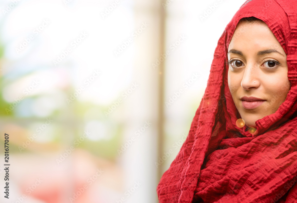 Young arab woman wearing hijab confident and happy with a big natural smile inviting to enter Young arab woman wearing hijab confident and happy with a big natural smile inviting to enter