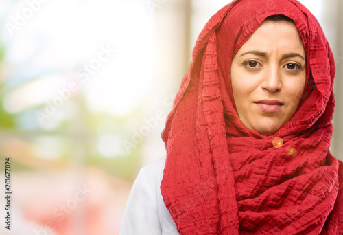 Young arab woman wearing hijab annoyed with bad attitude making stop sign with hand, saying no, expressing security, defense or restriction, maybe pushing