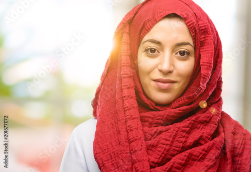 Young arab woman wearing hijab holding something, size concept