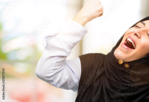 Young arab woman wearing hijab happy and excited celebrating victory expressing big success, power, energy and positive emotions. Celebrates new job joyful
