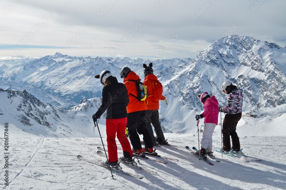 Familie in Skikleidung steht auf Ski, beim Schaufeljoch Panorama des Stubai Gletscher mit Sicht auf die Tiroler Berge