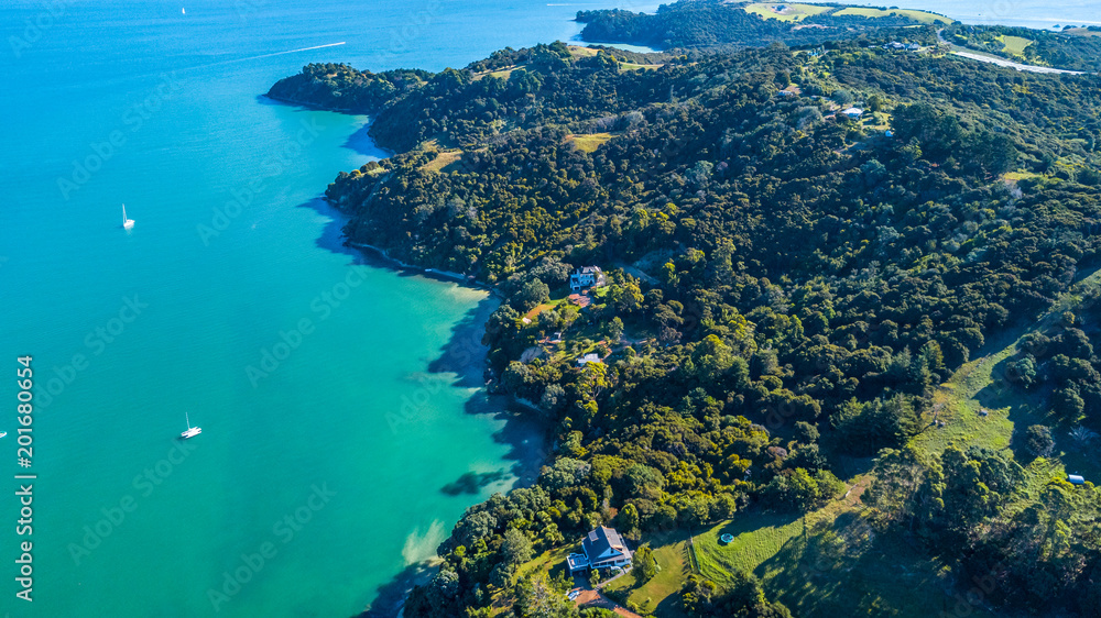 Aerial view on beautiful bay at sunny day with sandy beach and residential houses on the background. Waiheke Island, Auckland, New Zealand