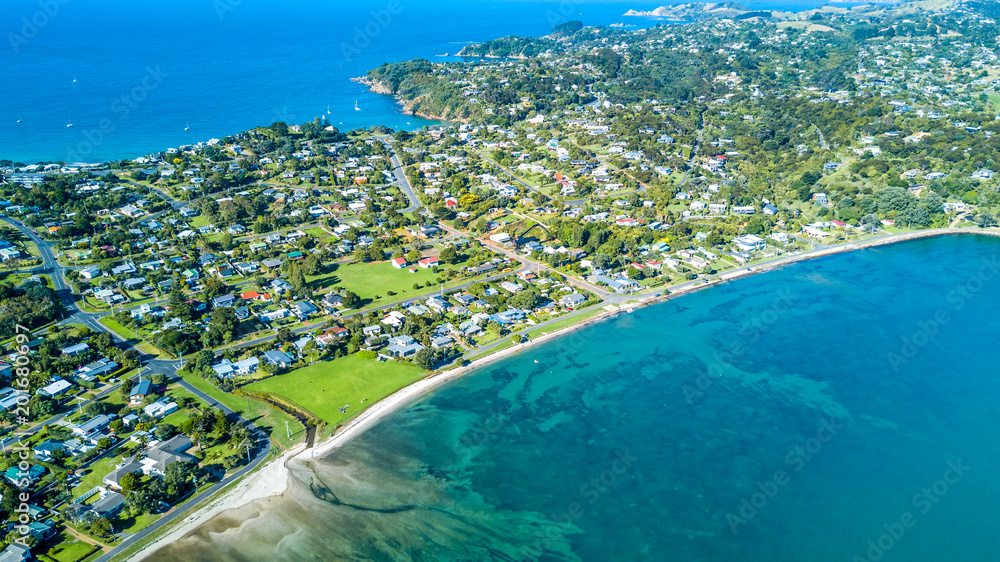Aerial view on beautiful bay at sunny day with sandy beach and residential suburbs on the background. Waiheke Island, Auckland, New Zealand