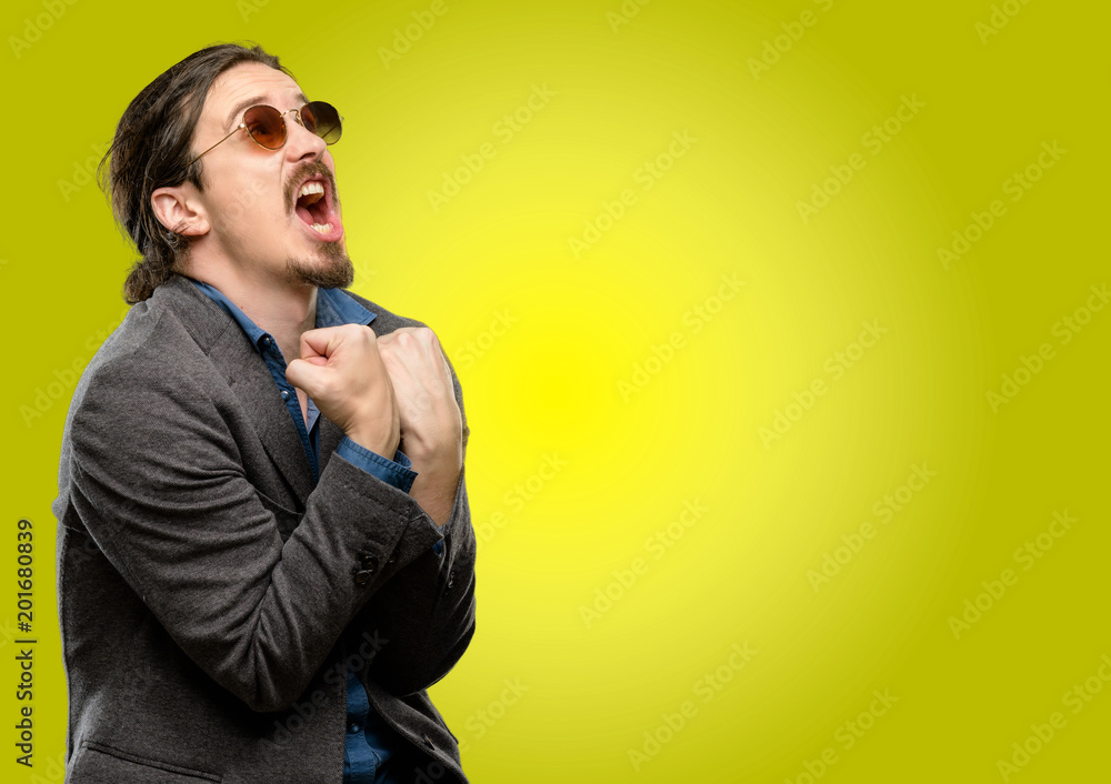 Handsome young man happy and excited celebrating victory expressing big success, power, energy and positive emotions. Celebrates new job joyful Handsome young man happy and excited celebrating victory expressing big success, power, energy and positive emotions. Celebrates new job joyful