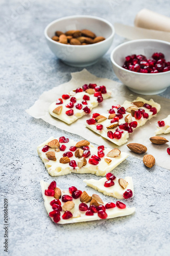 White chocolate pomegranate nuts holiday bark on concrete background. Selective focus, space for text.