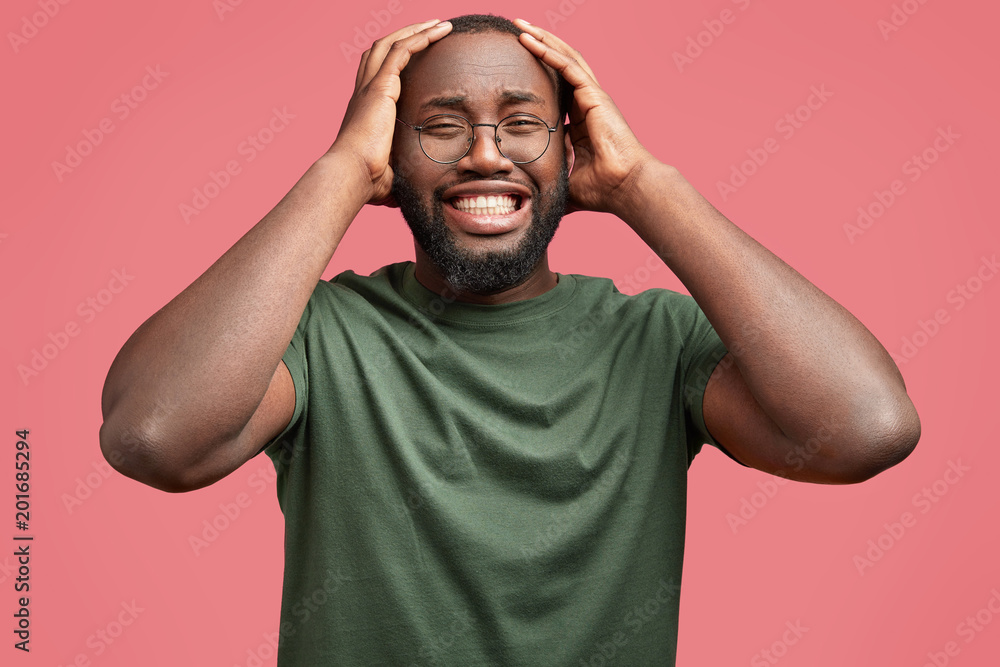 Sorrowful dark skinned male cries as being in depression, has big grief in life and unhappy expression, dressed in casual t shirt, isolated over pink background. African man has serious problem Sorrowful dark skinned male cries as being in depression, has big grief in life and unhappy expression, dressed in casual t shirt, isolated over pink background. African man has serious problem