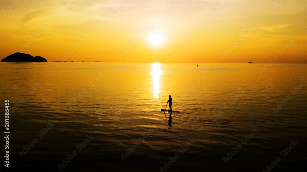 Aerial: Sunset silhouette of a person standing up at paddle board on vacation in Thailand Aerial: Sunset silhouette of a person standing up at paddle board on vacation in Thailand
