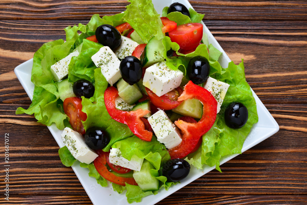Greek salad on a wooden background. Space for text or design. Greek salad on a wooden background. Space for text or design.