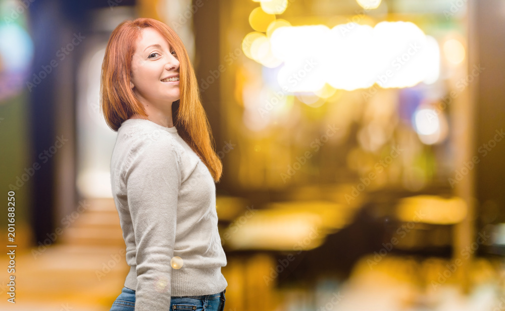 Beautiful young redhead woman confident and happy with a big natural smile laughing at night
