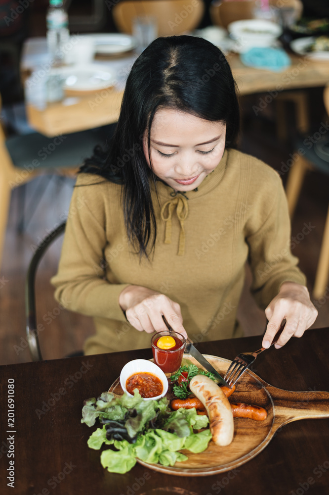 Woman holding knife and fork for eating food, Sausage with Tomato Sauce and green vegetable on wood plate