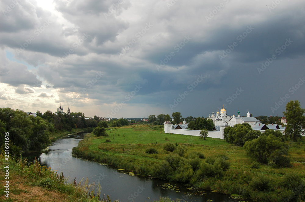 The river surrounds the old monastery. There's a storm coming. Suzdal, Russia