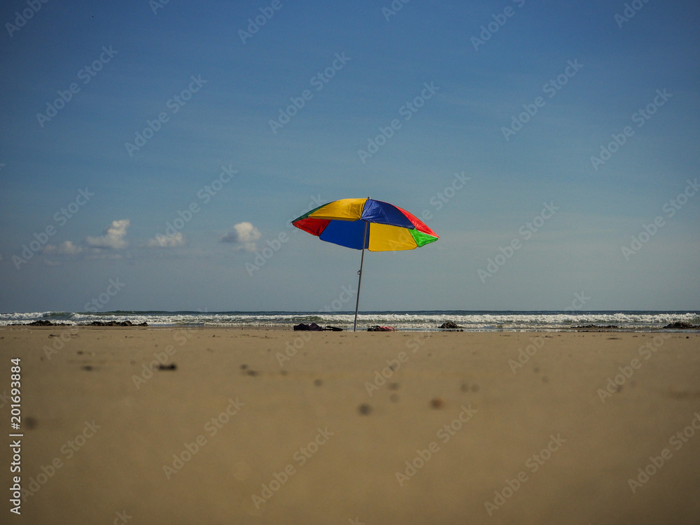 lonely colorful umbrella standing alone on a lonely beach in the carrebean