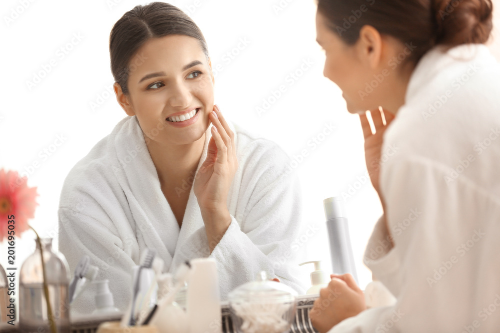Beautiful young woman looking at herself in mirror indoors Beautiful young woman looking at herself in mirror indoors