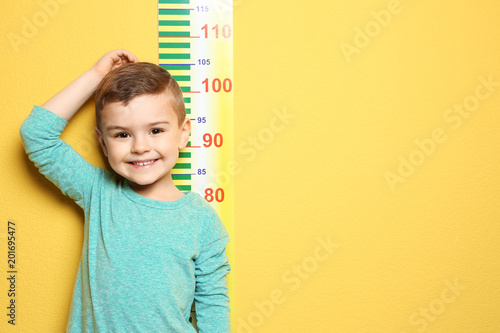 Принти на полотні Little boy measuring his height on color background
