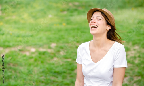 Happy brunette girl with hat laughing hard in the nature