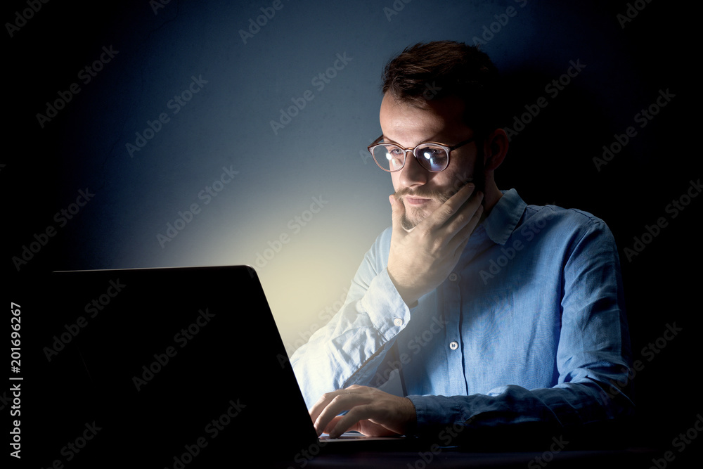 Young handsome businessman working late at night in the office with a dark background Young handsome businessman working late at night in the office with a dark background