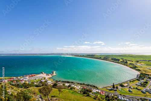 Fototapeta Naklejka Na Ścianę i Meble -  Stunning view point to big old volcanic rock mountain top called The Nut with blue turquoise water beach bay and green grass lands on warm sunny clear sky day, Stanley, North-West, Tasmania, Australia