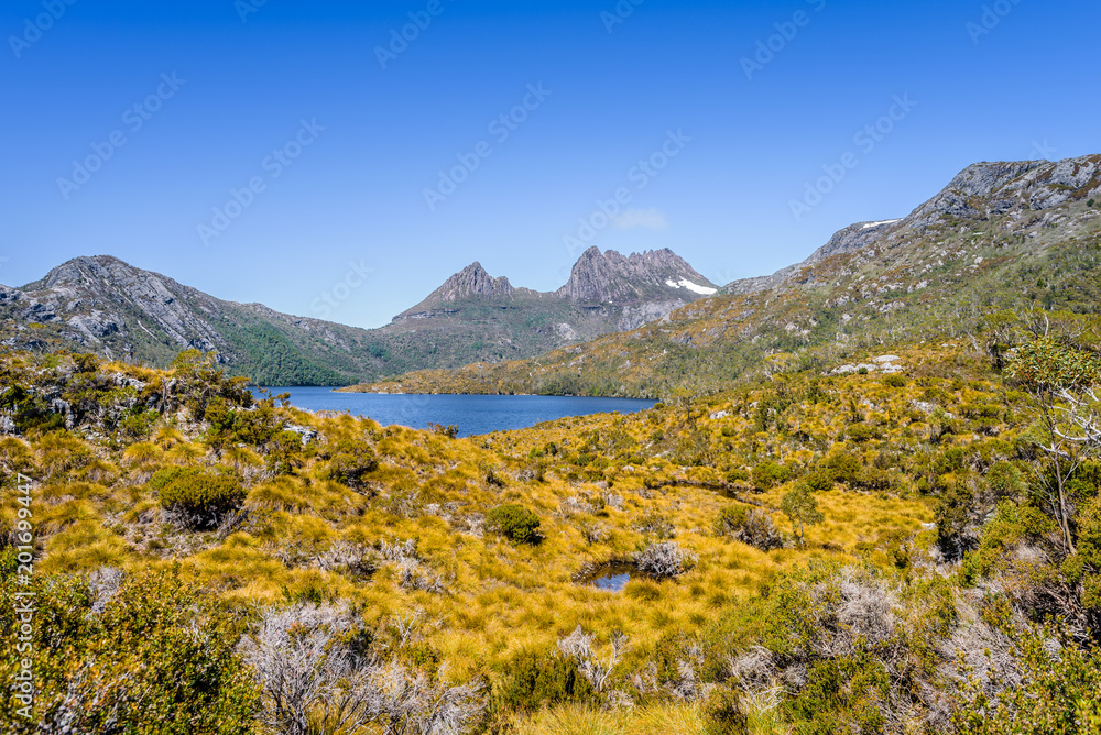 Pretty view to great deep blue mountain lake and green orange shore jungle forest bush land on warm sunny clear sky hiking wilderness day, Dove Lake, Cradle Mountain National Park, Tasmania, Australia Pretty view to great deep blue mountain lake and green orange shore jungle forest bush land on warm sunny clear sky hiking wilderness day, Dove Lake, Cradle Mountain National Park, Tasmania, Australia