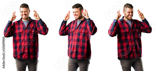 Young man with crossed fingers asking for good luck isolated over white background, collage composition