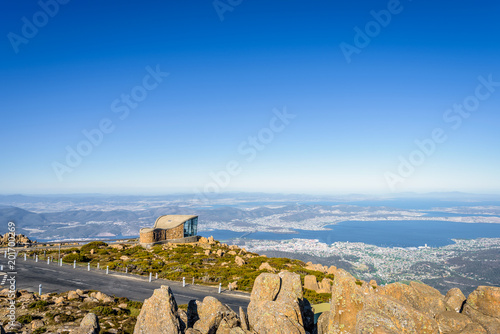 Stunning view from highest mountain peak to Hobart city blue sea ocean bay harbour and stones rocks grass lands on top after climbing on warm sunny clear sky day  Mount Wellington  Tasmania  Australia