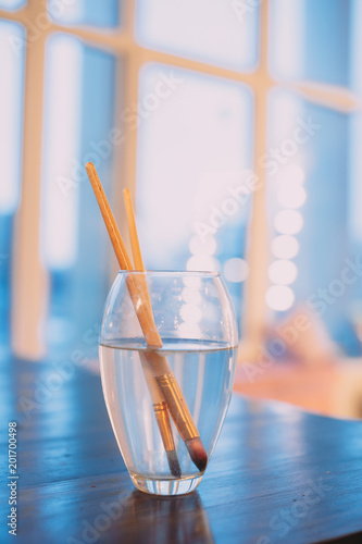 paint brushes in a glass of water. blue background photo