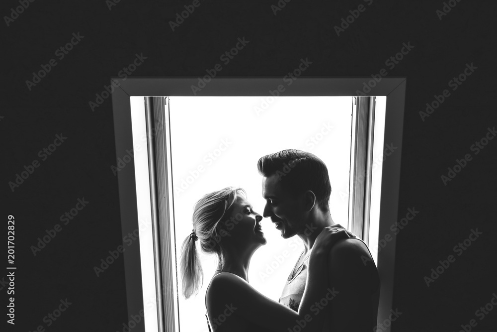 Lovely couple together at home. Pretty woman and attractive man wearing home clothes clothes standing near a window. Black and white photo Lovely couple together at home. Pretty woman and attractive man wearing home clothes clothes standing near a window. Black and white photo
