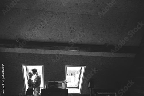 Lovely couple together at home. Pretty woman and attractive man wearing home clothes clothes standing near a window. Black and white photo