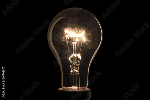 Realistic light bulb on the black background. Lamp light in the dark. Electric bulb. Glowing light in the dark. photo
