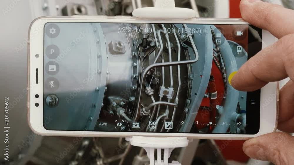 A man engineer photographs a jet engine. The man's hand takes a picture ...