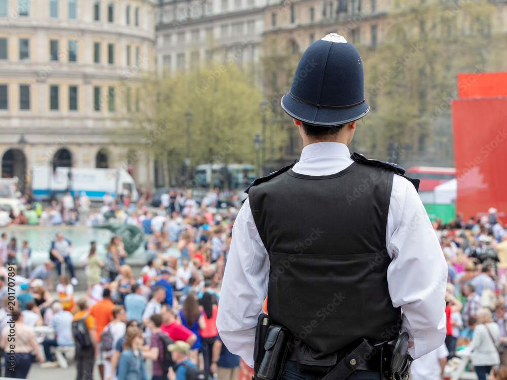 Obraz premium Rear view of Police Officer Watching Over Crowds in Trafalgar Square, London