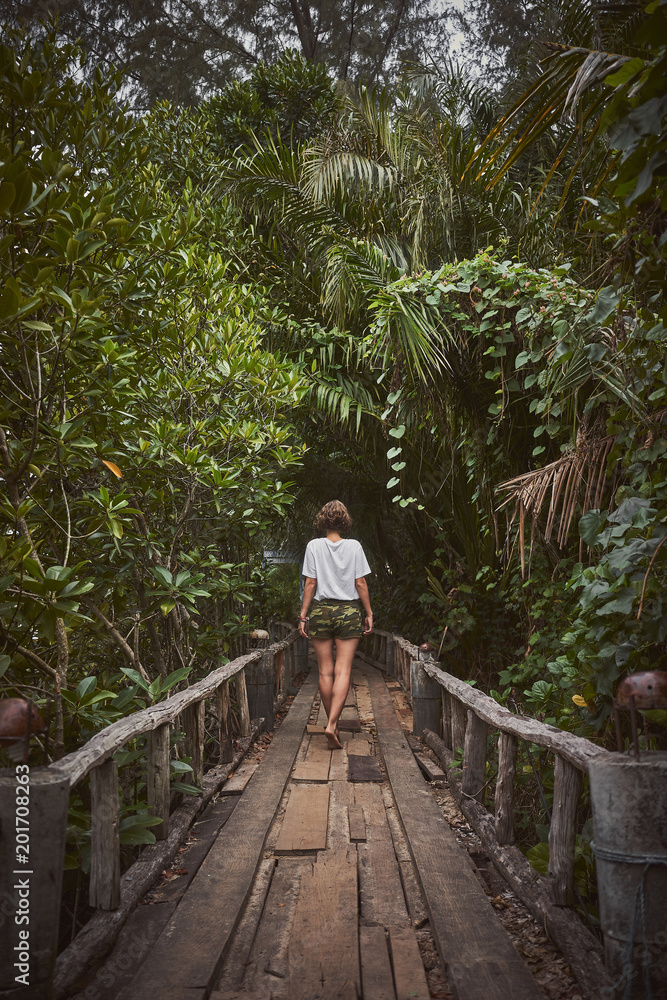 Traveling girl on the wooden bridge. Pretty young woman in the jungle. Summer lifestyle and adventure photo Traveling girl on the wooden bridge. Pretty young woman in the jungle. Summer lifestyle and adventure photo