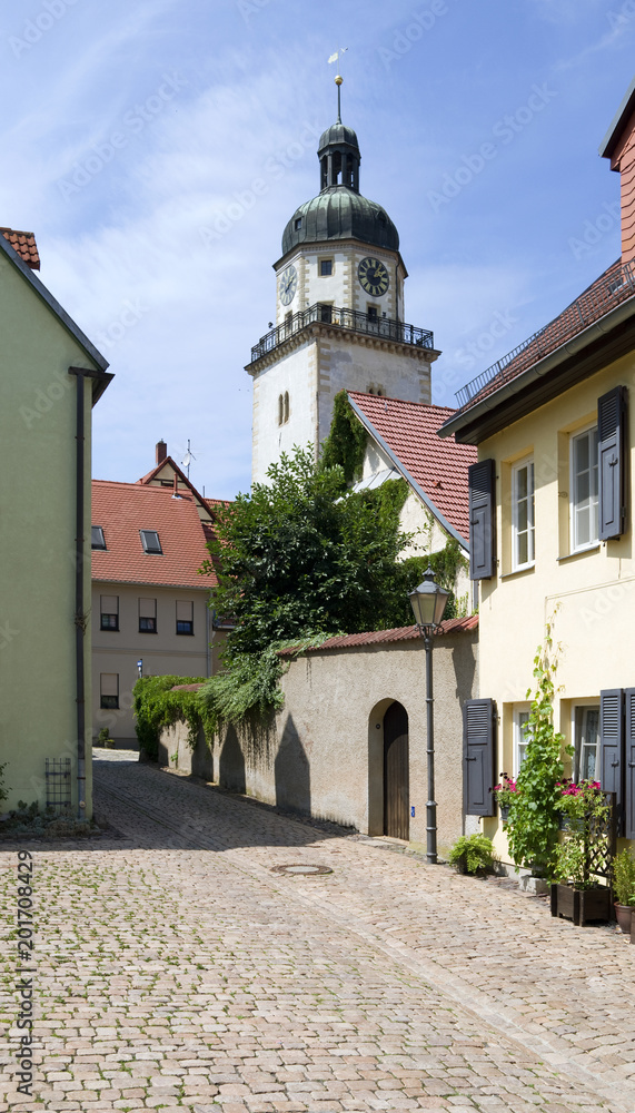 Altenburg / Germany: View through a narrow cobblestone alley to the romanesque Nikolai tower in the heart of the historic Nikolai quarter on a beautiful summer day