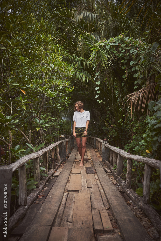 Traveling girl on the wooden bridge. Pretty young woman in the jungle. Summer lifestyle and adventure photo