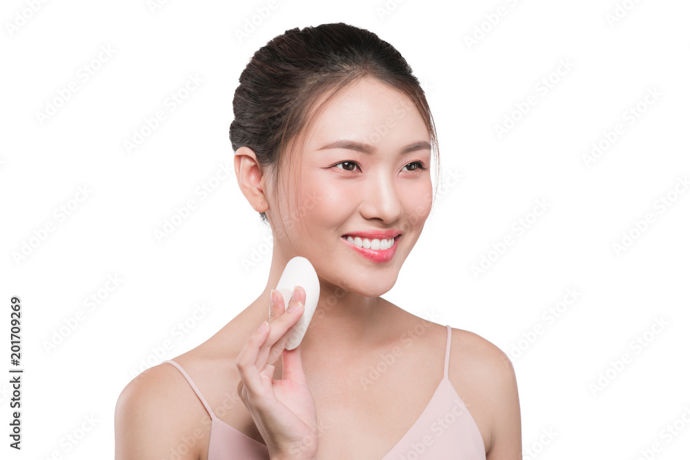Cute girl with black hair applying powder on her face with powder puff Cute girl with black hair applying powder on her face with powder puff