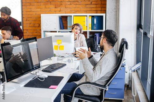 young male employee is accompaning his speach with gestures at workplace. chat among co-workers photo