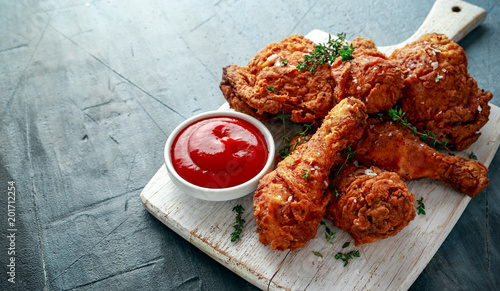 Slika na platnu Fried crispy chicken legs, Thigh on white cutting board with ketchup and herbs