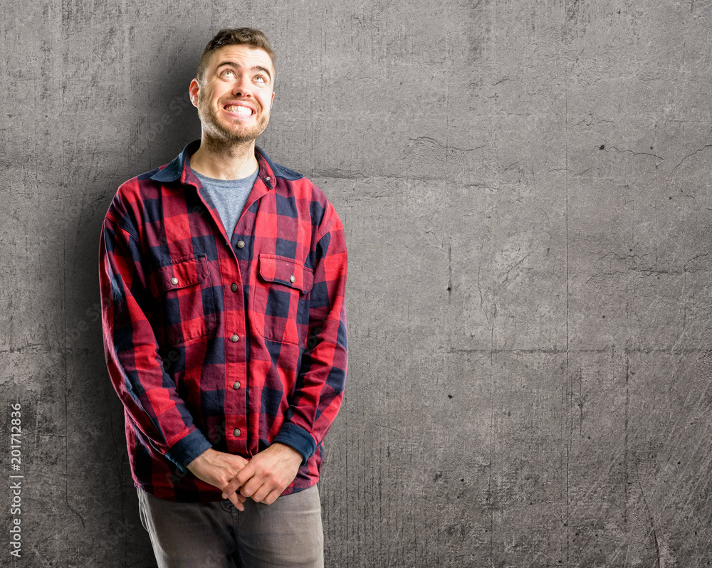 Young handsome man confident and happy with a big natural smile laughing looking up Young handsome man confident and happy with a big natural smile laughing looking up