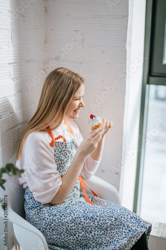 happy Laughing young woman having cupcake while sitting near window. photo