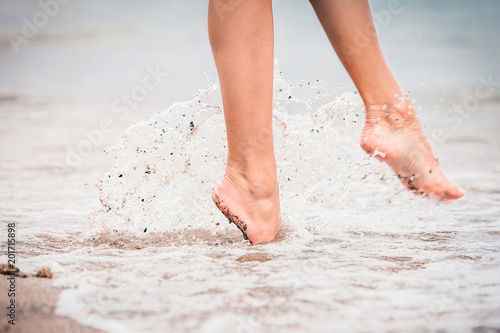 Canvas Print girl comes barefoot into the water in the summer at sea