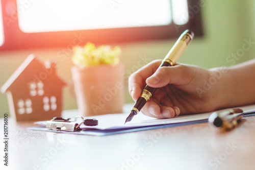 Human hand suing pen with supplies working for business.