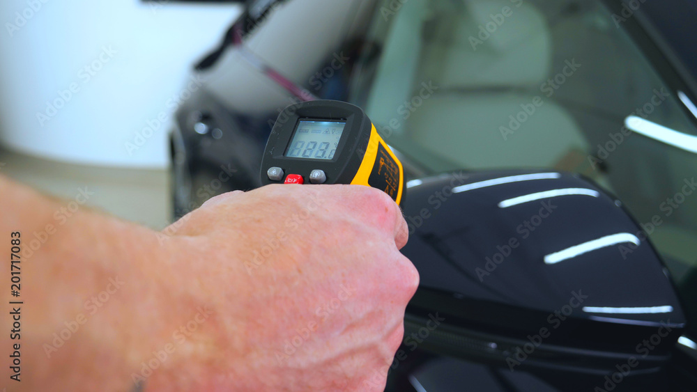 The professional worker holds a pistol in his hand measuring the temperature of the auto repair shop, car washing. The professional worker holds a pistol in his hand measuring the temperature of the auto repair shop, car washing.
