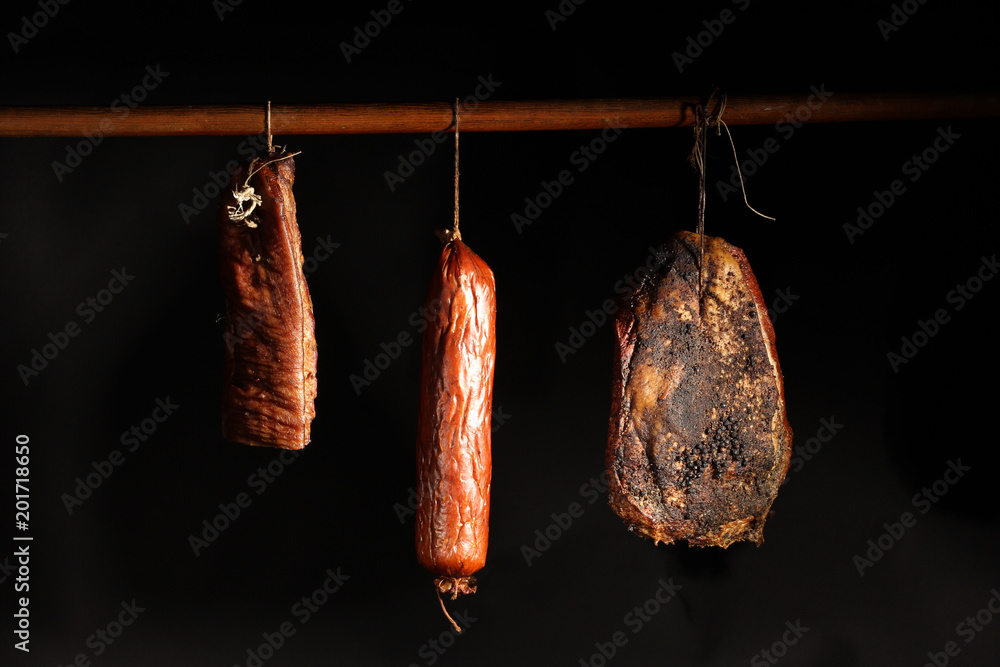 Fototapeta premium Wędzonki. Kompozycja wędzonych wędlin na czarnym tle.