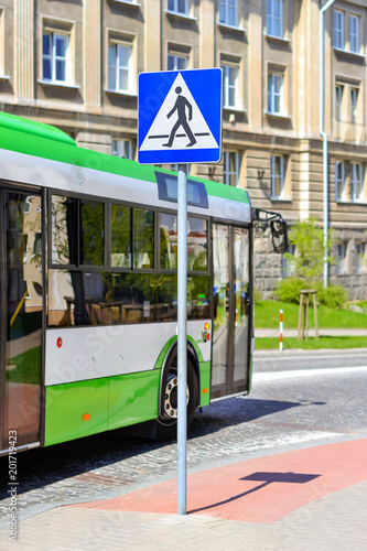 Passenger bus drives past the sign crosswalk on Central cobblestone paved road in Bialystok, Poland. Comfortable urban public transport and developed road infrastructure in Eastern Europe