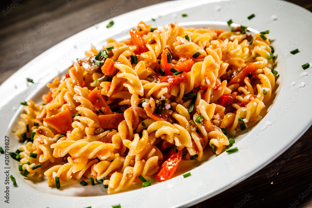 Pasta with tomato sauce and vegetables on wooden table Pasta with tomato sauce and vegetables on wooden table